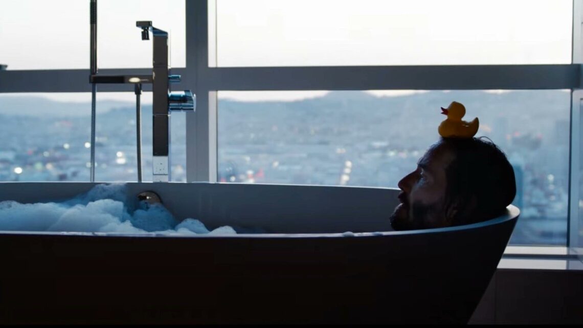 Neo liegt in der Badewanne mit einer Gummiente auf dem Kopf