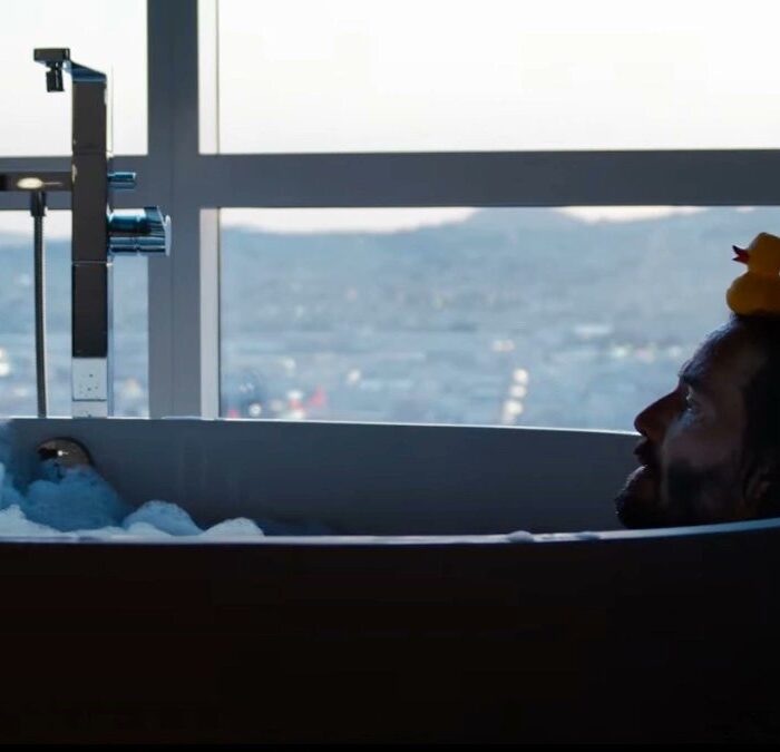 Neo liegt in der Badewanne mit einer Gummiente auf dem Kopf