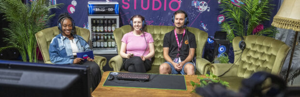Foto vom Indie Arena Booth Streaming Studio in dem 3 Personen auf einer Couch sitzen und spielen. Foto: Koelnmesse / gamescom