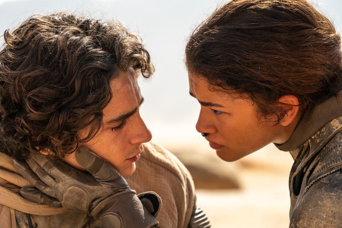 Szene aus dem Film Dune 2. Eine junge Frau legt die Hand auf die Wange eines jungen Mannes. Im Hintergrund Wüste.