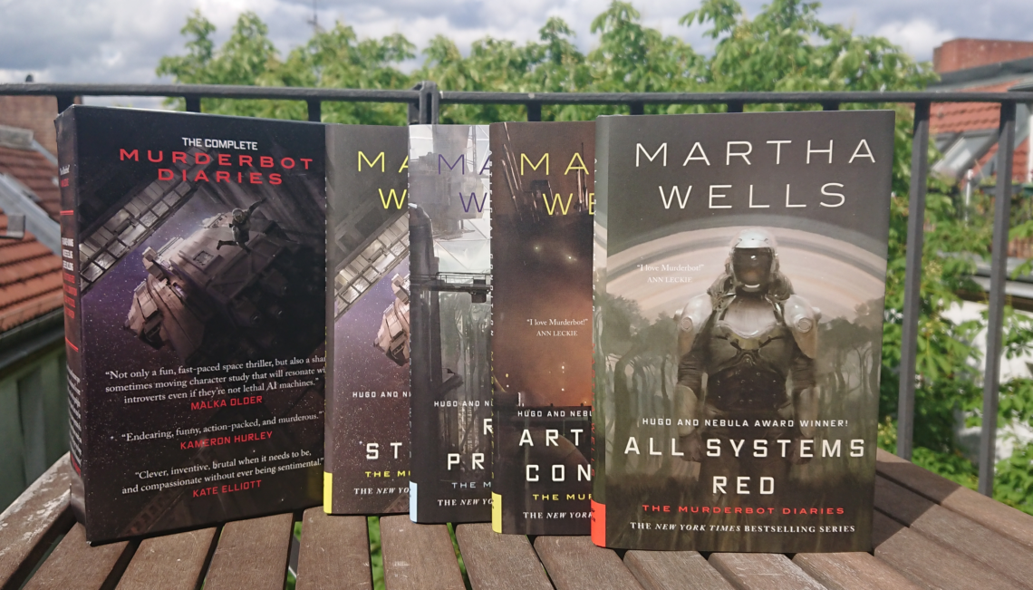 Foto der Buchreihe Murderbot. Die 4 Bände stehen aufgereiht hintereinander auf einem Holztisch.