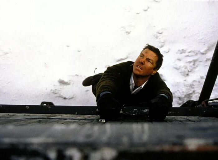 Szene aus einem Film mit Dennis Quaid, der sich verzweifelt an einer Metallstange festhelt
