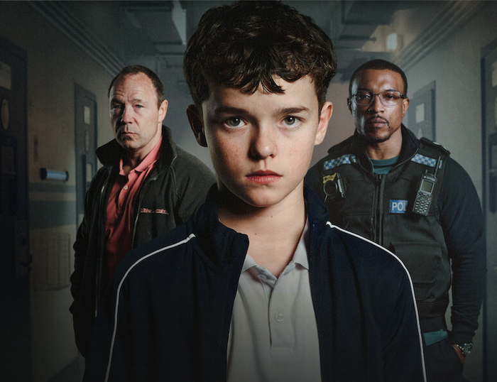 Werbeposter für die Serie Adolesence. Ein 13 jähriger Junge in der Mitte, links dahinter ein etwa 40 jähriger weißer Mann, rechts dahinter ein etwa 40 jähriger schwarzer Mann