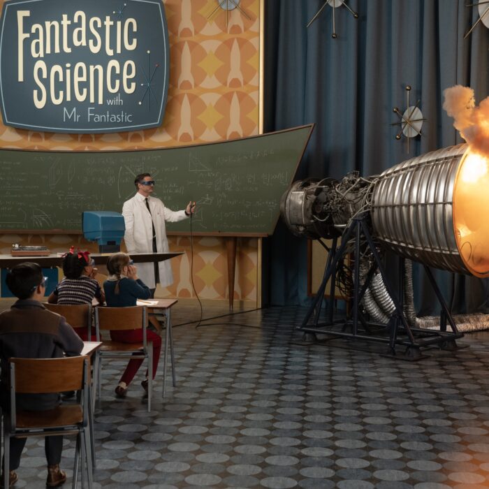 Filmszene aus Fantastic Four. Ein Mann im Laborkittel steht in einem Klassenraum und demonstriert eine Raktenantriebszündkapsel
